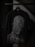 Black oversized graphic T-shirt featuring a minimalist white abstract line-art design on the back, displayed on a premium wooden hanger against a dark studio background.