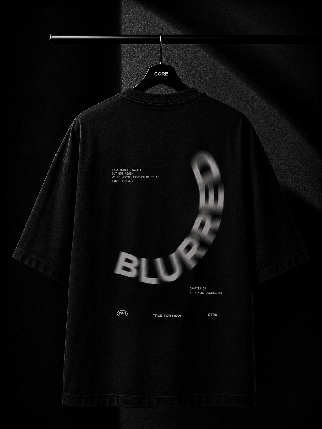 Premium black oversized T-shirt hanging on a wooden hanger featuring a minimalist white Japanese maple leaf print cascading from the right shoulder onto the chest. Studio product photography with a dark luxury background.