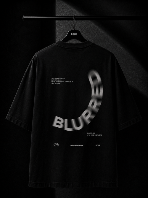 Premium black oversized T-shirt hanging on a wooden hanger featuring a minimalist white Japanese maple leaf print cascading from the right shoulder onto the chest. Studio product photography with a dark luxury background.