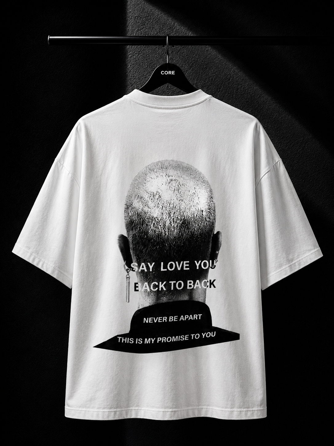 White oversized T-shirt featuring a monochrome back graphic of a shaved head with bold typography in a premium minimalist streetwear design.
